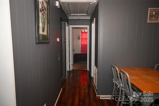 hall featuring dark wood-type flooring and wood walls