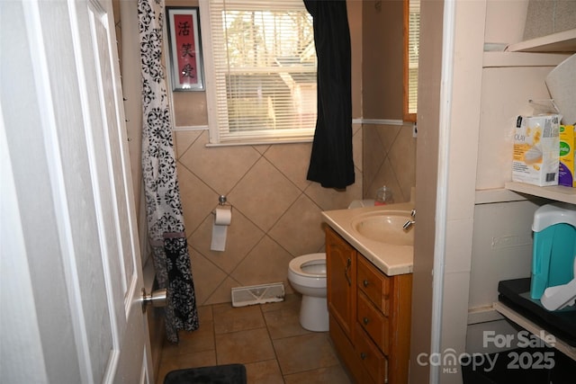 bathroom with a shower with shower curtain, tile patterned flooring, tile walls, toilet, and vanity