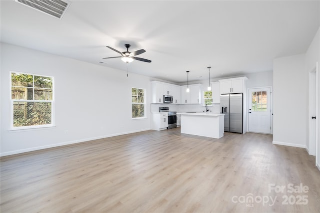 unfurnished living room featuring sink, ceiling fan, a wealth of natural light, and light hardwood / wood-style floors