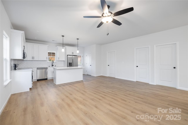 kitchen with sink, white cabinets, hanging light fixtures, a kitchen island, and appliances with stainless steel finishes