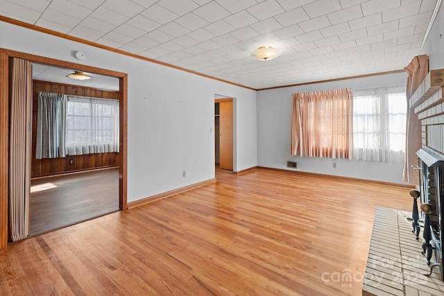 unfurnished living room featuring light hardwood / wood-style floors, crown molding, and a fireplace