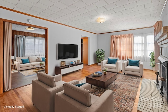 living room with ornamental molding, light wood-type flooring, and a fireplace