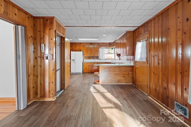 kitchen featuring dark wood-type flooring, kitchen peninsula, and white fridge with ice dispenser