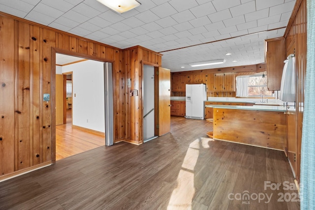 kitchen with sink, light hardwood / wood-style floors, white fridge with ice dispenser, and kitchen peninsula