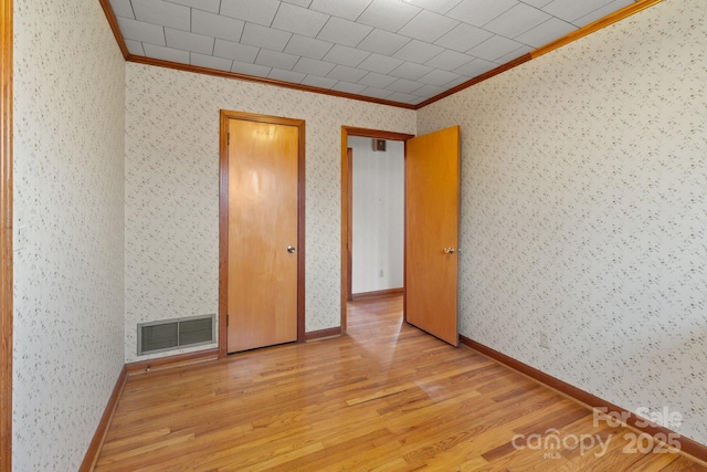 empty room featuring ornamental molding and light hardwood / wood-style floors