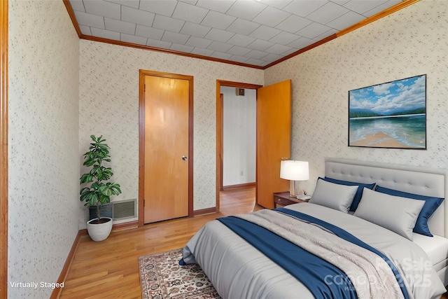 bedroom with light wood-type flooring and crown molding