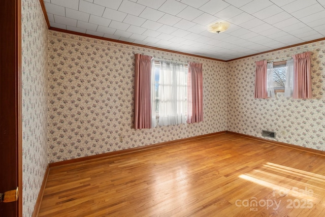 spare room with ornamental molding, wood-type flooring, and plenty of natural light