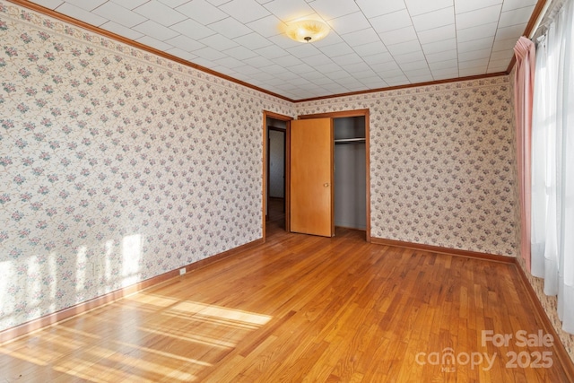 unfurnished bedroom featuring wood-type flooring, a closet, and ornamental molding