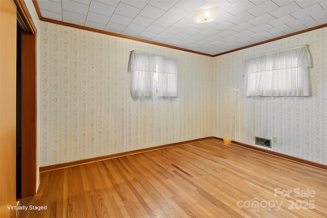 empty room with hardwood / wood-style flooring and ornamental molding