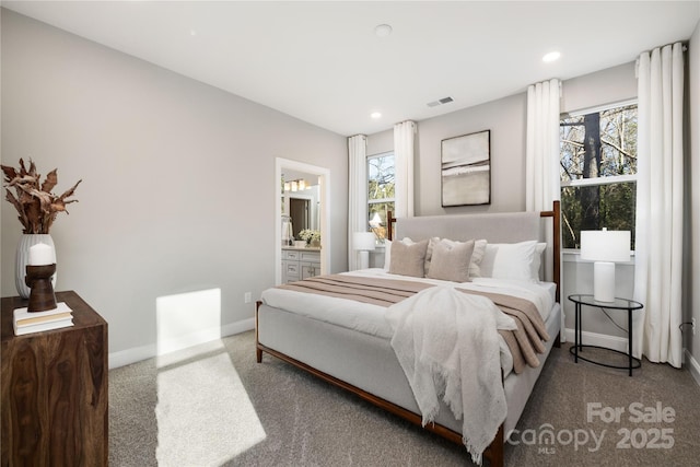 carpeted bedroom featuring multiple windows and ensuite bath