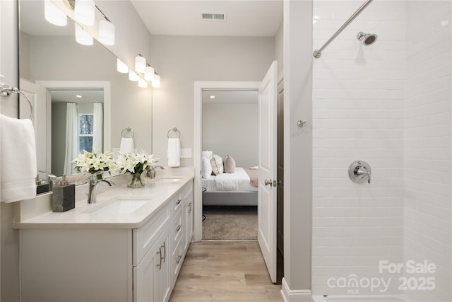 bathroom with hardwood / wood-style flooring, vanity, and tiled shower