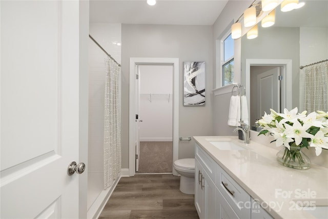 bathroom featuring walk in shower, vanity, wood-type flooring, and toilet