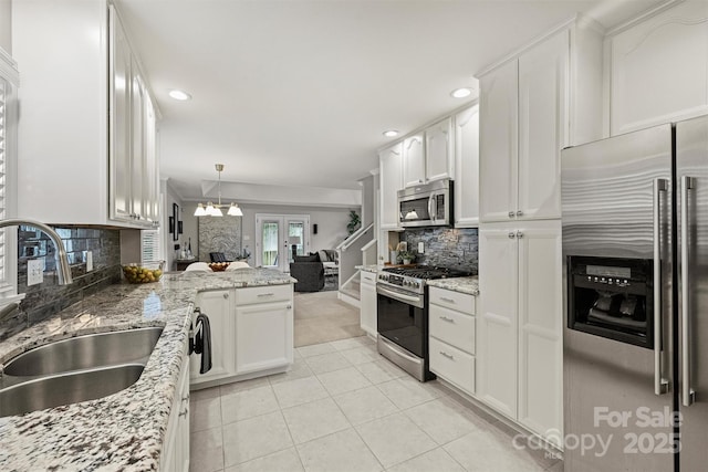 kitchen featuring appliances with stainless steel finishes, sink, light stone counters, and white cabinets