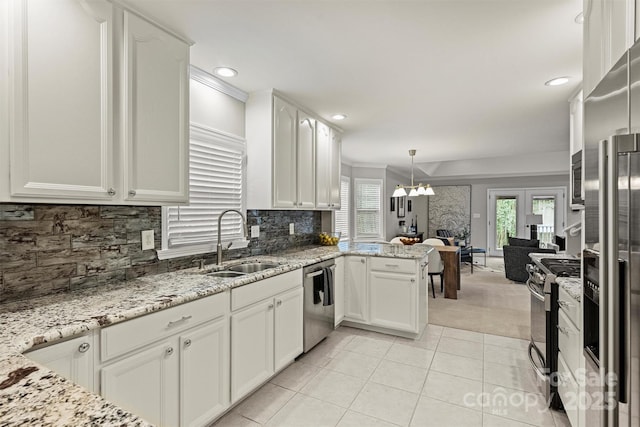 kitchen with stainless steel appliances, hanging light fixtures, sink, light stone counters, and white cabinets