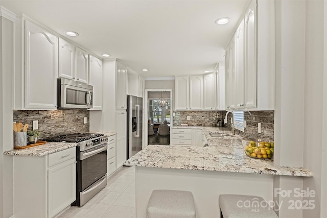 kitchen featuring kitchen peninsula, appliances with stainless steel finishes, white cabinets, and light stone countertops