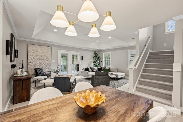 dining room featuring crown molding, a raised ceiling, french doors, and a healthy amount of sunlight