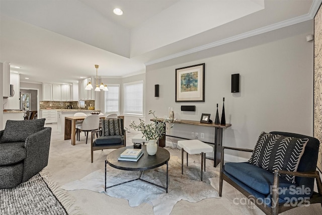 living room with light carpet, a chandelier, a tray ceiling, and ornamental molding