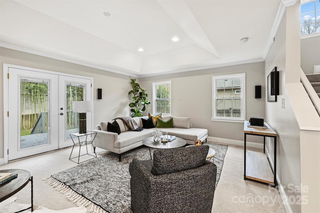 living room with a tray ceiling, french doors, crown molding, and light carpet