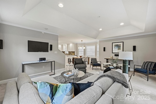 living room with a tray ceiling, ornamental molding, light carpet, and an inviting chandelier