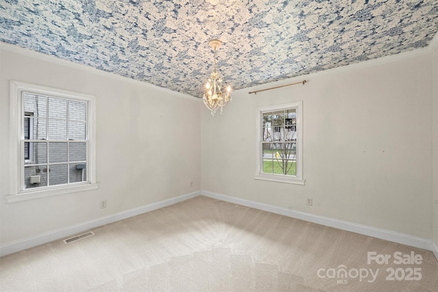 spare room featuring carpet, crown molding, and an inviting chandelier