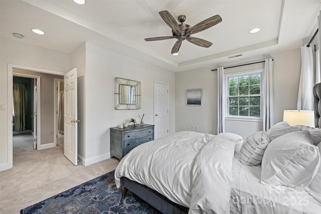 carpeted bedroom with a tray ceiling and ceiling fan