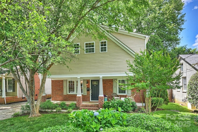 view of front of home featuring a porch, brick siding, and a front yard