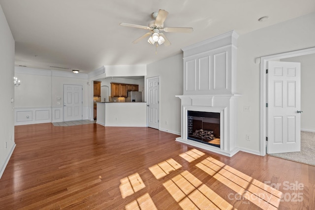 unfurnished living room with ceiling fan, a large fireplace, and light hardwood / wood-style floors