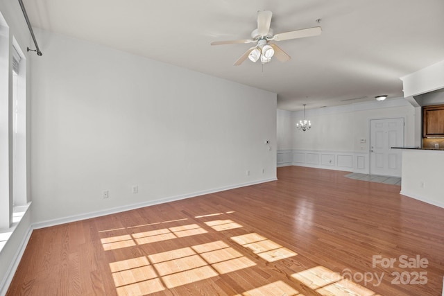 unfurnished living room with ceiling fan with notable chandelier and light wood-type flooring