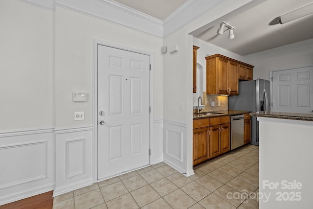 kitchen featuring sink, crown molding, decorative backsplash, light tile patterned floors, and appliances with stainless steel finishes