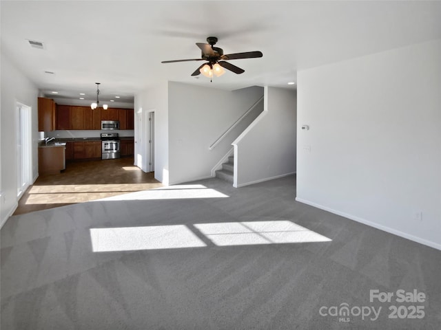 unfurnished living room with ceiling fan with notable chandelier, dark carpet, and sink