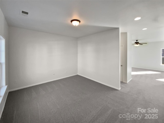 unfurnished room with dark colored carpet and ceiling fan