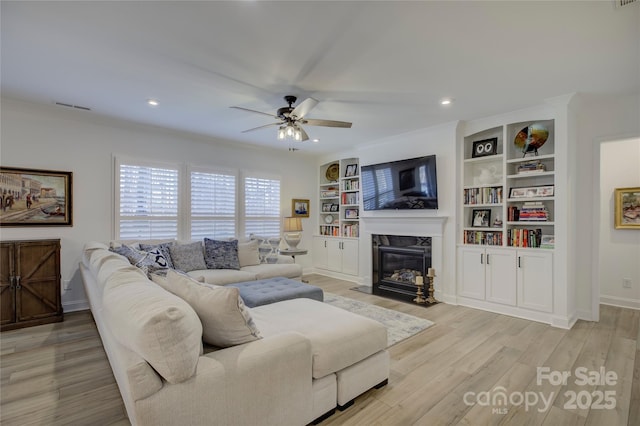 living room with a fireplace, visible vents, ceiling fan, light wood-type flooring, and baseboards