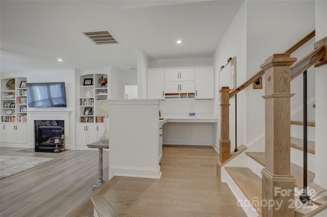 interior space with built in shelves, recessed lighting, wood finished floors, visible vents, and a high end fireplace