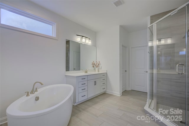 full bathroom with a stall shower, baseboards, visible vents, vanity, and a freestanding tub