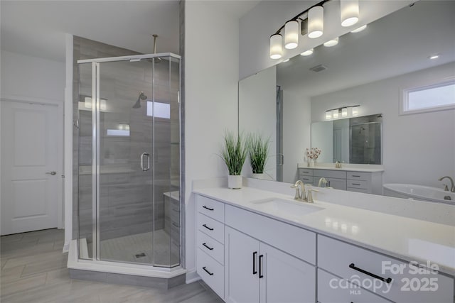 full bathroom featuring a stall shower, vanity, and visible vents