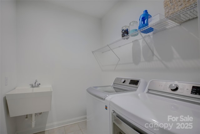 laundry room featuring light tile patterned floors, a sink, separate washer and dryer, laundry area, and baseboards