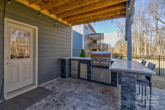 view of patio / terrace with outdoor wet bar, a grill, an outdoor kitchen, and fence