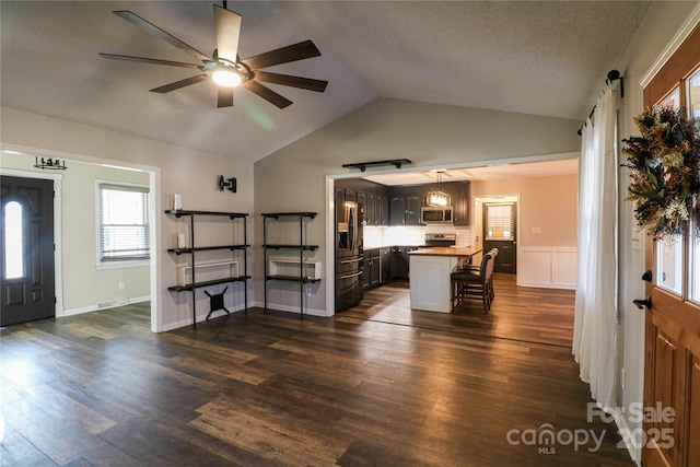 interior space with dark brown cabinetry, ceiling fan, a breakfast bar area, a kitchen island, and appliances with stainless steel finishes