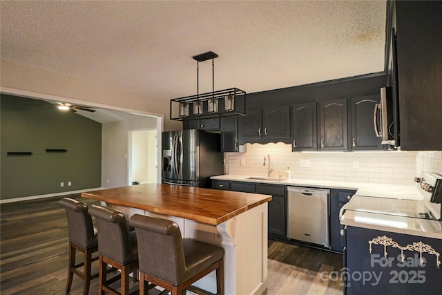 kitchen with wood counters, sink, dark hardwood / wood-style floors, a kitchen island, and stainless steel appliances