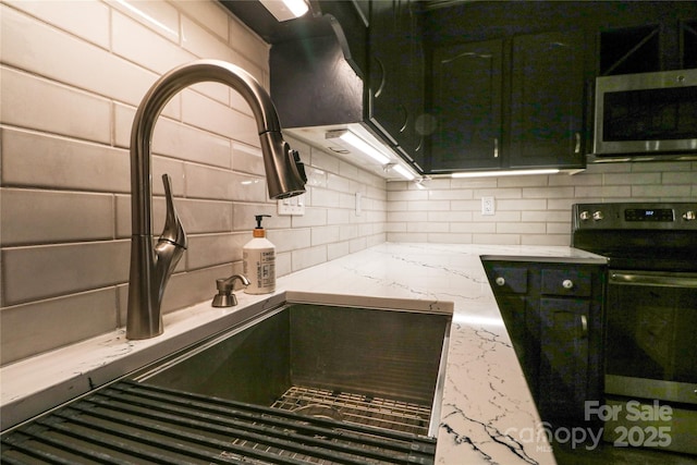 kitchen featuring light stone countertops, stove, backsplash, and sink