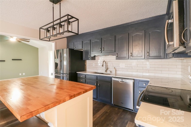 kitchen featuring dark wood-type flooring, sink, a textured ceiling, decorative light fixtures, and stainless steel appliances