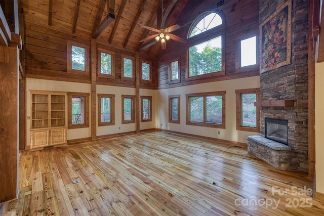 unfurnished living room with wooden ceiling, high vaulted ceiling, light hardwood / wood-style flooring, a fireplace, and beamed ceiling