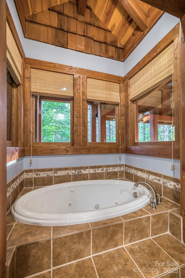 bathroom featuring lofted ceiling with beams, tiled bath, and wood ceiling