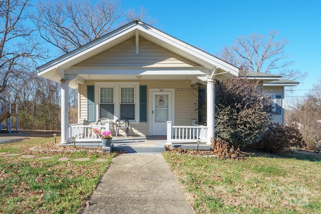 bungalow-style house featuring covered porch and a front lawn