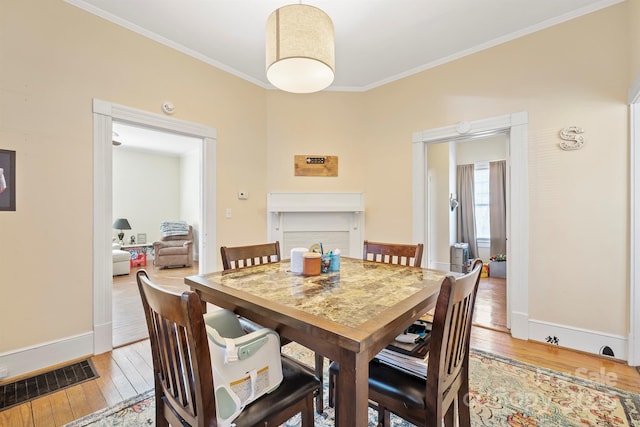 dining space featuring light wood-type flooring and ornamental molding