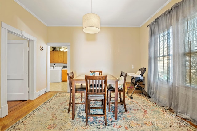 dining space featuring light wood-type flooring, ceiling fan, ornamental molding, and washing machine and clothes dryer