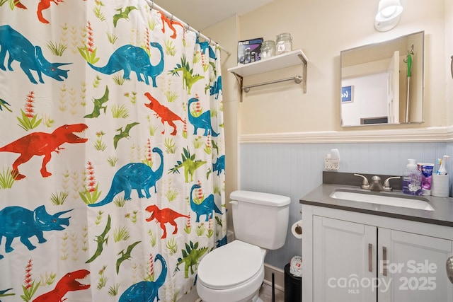 bathroom with a shower with shower curtain, vanity, wood walls, and toilet