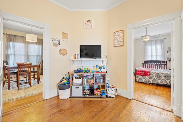 game room featuring wood-type flooring, ceiling fan, and ornamental molding