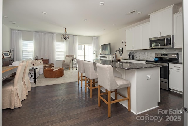 kitchen with dark hardwood / wood-style flooring, a center island with sink, stainless steel appliances, and sink