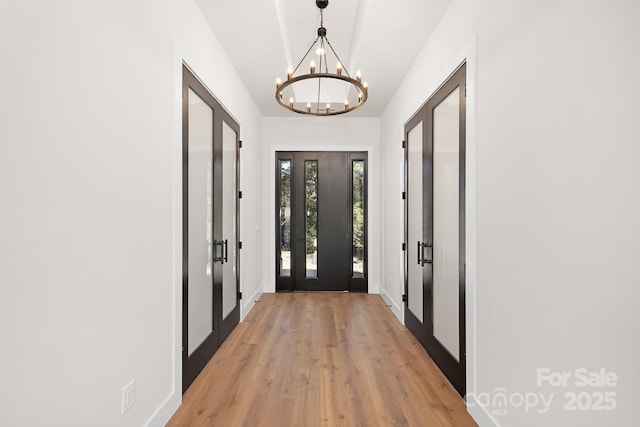 doorway to outside with a chandelier and light hardwood / wood-style floors